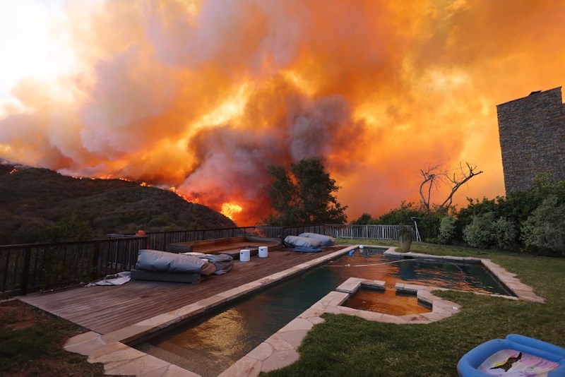 Thousands flee as wildfires burn out of control in and around Los Angeles and homes are destroyed